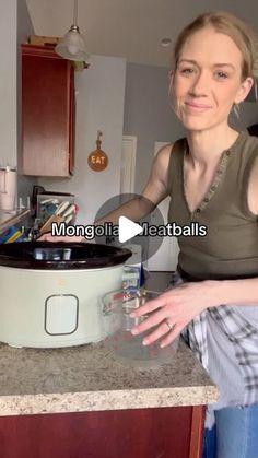 a woman standing in front of a crock pot on top of a kitchen counter