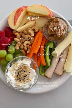 an apple, carrots, grapes, cashews and other food items on a plate