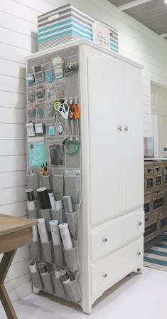 a white cabinet filled with lots of items in a room next to a wooden table