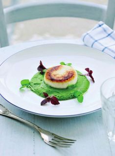 a white plate topped with food on top of a table next to a fork and knife