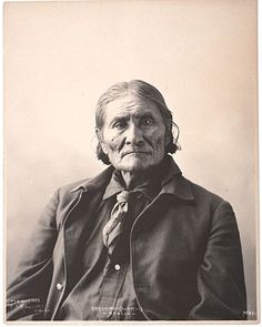 an old photo of a man with long hair and wearing a jacket, tie and pants