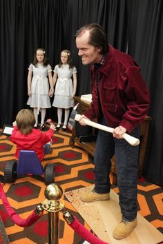 a man standing on top of a stage holding a baseball bat next to children in front of him