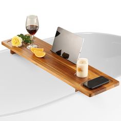 a laptop computer sitting on top of a wooden tray next to a glass of wine