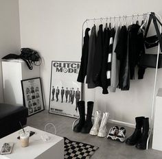 a black and white photo of clothes hanging on a rack in a room with shoes