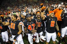 a group of football players standing on top of a field holding up their arms in the air