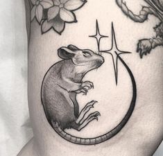 a rat sitting on the side of a woman's thigh with flowers around it