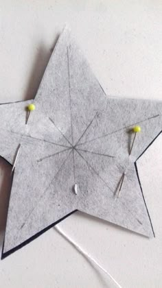 an origami star with pins and needles attached to the side, sitting on a white surface