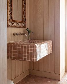 a bathroom with wood paneling and a mirror above the sink in front of it