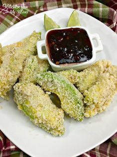 some fried food on a white plate with dipping sauce in the middle and an avocado wedge