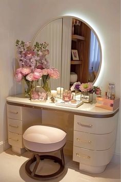 a vanity with flowers and candles on it in front of a round mirror that is lit up