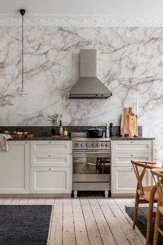 a kitchen with marble walls and flooring next to a stove top oven on a wooden floor