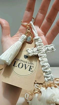 a hand is holding a keychain that has a cross and tassel on it