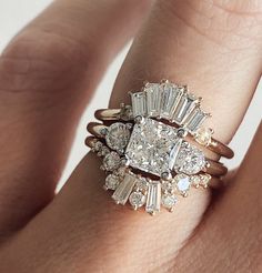 a woman's hand with a diamond ring on top of her finger and an engagement band