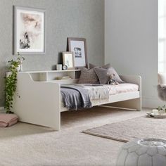 a white day bed sitting on top of a carpeted floor next to a window