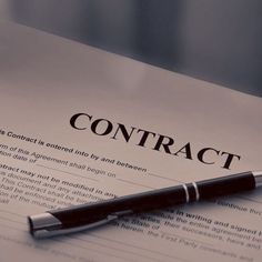 a pen sitting on top of a paper with the word contract written in black ink