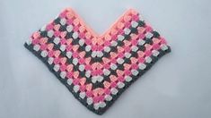 a crocheted pink and gray triangle on a white surface