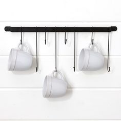 three coffee cups hanging from hooks on a wall