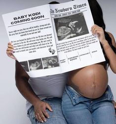 a pregnant woman holding up a baby kopi coming soon sign while sitting on her stomach