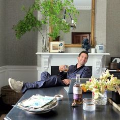 a man sitting at a table with his feet on the coffee table and holding a wine glass