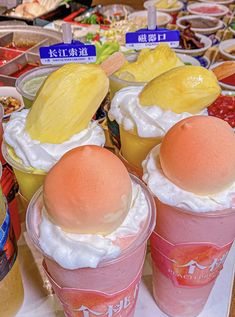 several desserts are arranged in plastic cups on a table with fruit and ice cream