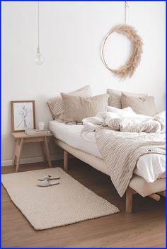 a bed with white sheets and pillows in a room next to a rug on the floor