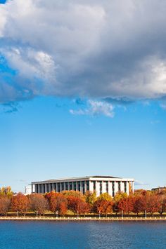 a large building sitting on top of a lush green field next to a body of water