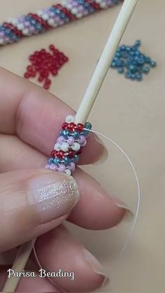 a person holding a stick with beading on it and some beads in the background