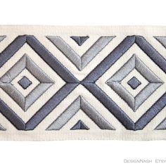 a white and gray rug with diamond shapes on it