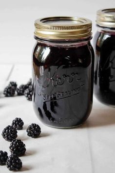 two jars filled with blackberries sitting on top of a table