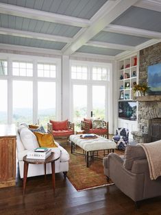 a living room filled with furniture and a fire place next to a window covered in lots of windows