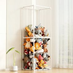 a white shelf filled with stuffed animals on top of a wooden floor next to a window