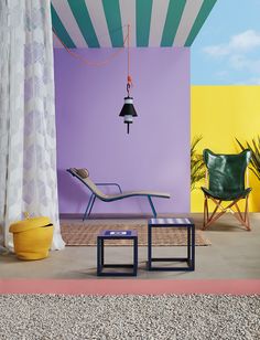 a chair and table in front of a colorful wall with a lamp hanging over it