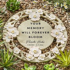 a memorial stone surrounded by plants and rocks with the words your memory will forever bloom