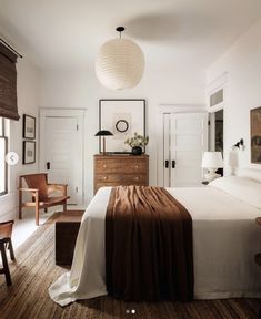 a bedroom with white walls and wooden furniture, along with a bed that has a brown blanket on it