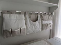 several pockets are hanging on the wall next to a bed with white sheets and pillows