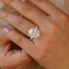 a woman's hand holding an engagement ring with a diamond in the center and two diamonds on each side