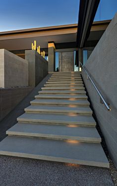 the stairs are made of concrete and lead up to an open area with large windows