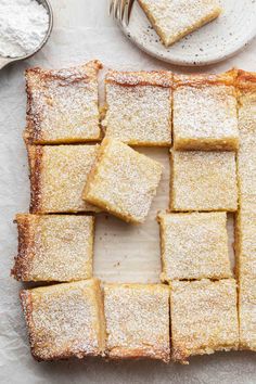 several pieces of cake sitting on top of a cutting board next to a plate with powdered sugar