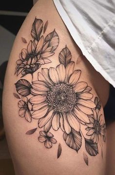 a sunflower tattoo on the side of a woman's thigh