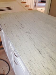 a white counter top in a kitchen next to a stair case and door leading to another room