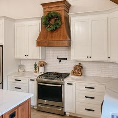 a kitchen with white cabinets and an oven in the center, surrounded by christmas wreaths