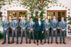 a group of men standing next to each other in front of a building with flowers on it