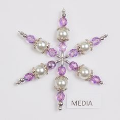 a snowflake brooch with pearls and amethyst purple crystals on it