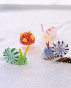 three small toy snails sitting on top of snow covered ground next to each other