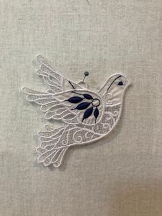 a white bird with blue accents on it's wings is sitting on a piece of fabric