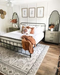 a bedroom with a bed, dressers and mirrors on the wall above it's headboard