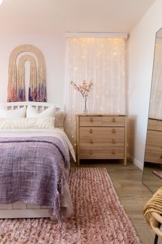 a bedroom with a bed, dresser and mirror on the wall next to a window