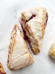 two pastries sitting next to each other on top of a white paper covered in icing