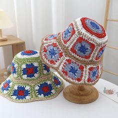 two crocheted hats sitting on top of a white table next to each other