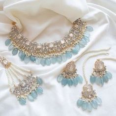 a necklace and earring set on a white cloth with pearls, beads and stones